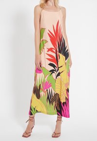 Robe maxi sans manches rose clair avec un imprimé tropical vibrant en vert, rouge, noir et rose. Dotée de fines bretelles et d'une texture lisse.