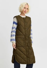 Olivgrüne Steppweste mit gestepptem Design, mit Druckknöpfen, seitlichen Taschen und einem hohen Schlitz am Saum für Bewegungsfreiheit.