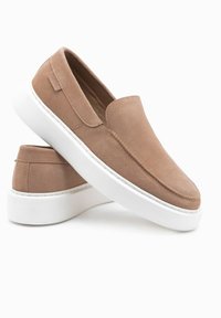 Kavové kožené slip-on boty s bílou gumovou podrážkou, s hladkým povrchem, zaoblenou špičkou a minimalistickým designem. Žádné viditelné kovové prvky.