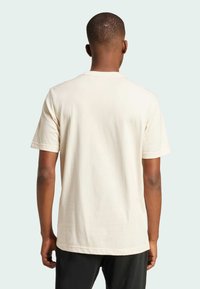 Svetlo béžové tričko s krátkymi rukávmi, oválnym výstrihom a voľným strihom. Vyrobené z bavlny, s hladkou textúrou a bez viditeľných vzorov.