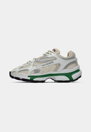 Sneakers Lacoste con tomaia in rete bianca con accenti argento e suola verde, progettati con una forma spessa e imbottita.