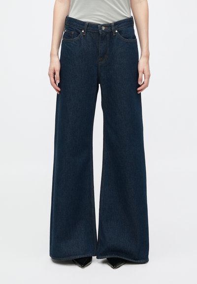 Φαρδιά τζιν παντελόνια από σκούρο denim με ψηλή μέση, διαθέτουν πέντε τσέπες και αντίθετη ραφή. Λείος υφασμάτινος ιστός και κοπή full-length.