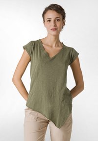 Tricou scurt din bumbac de culoare verde măslin, cu decolteu în V și tiv asimetric. Fabricat dintr-un material texturat, având o croială lejeră și detalii cu cusături diagonale.