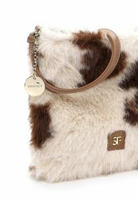Borsa in pelliccia sintetica con stampa a macchie di mucca, dotata di una tracolla in pelle marrone e accessori in oro. Caratterizzata da un'etichetta con marchio e una superficie testurizzata e soffice.