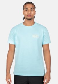 Camiseta de algodón azul claro con cuello redondo, mangas cortas y un pequeño logo en dorado que dice "WRONG FRIENDS" en el lado izquierdo del pecho.
