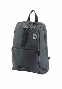 Mochila negra de nailon con respaldo acolchado, bolsillo frontal con cremallera, detalle de logo y correas ajustables. Presenta una textura suave y una forma estructurada.