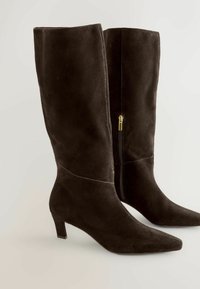 Black suede knee-high boots with a pointed toe, low block heel, and a gold zipper along the side. Smooth texture with minimalist design.