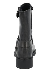 Botín negro de cuero hasta el tobillo con cierre de cremallera, una correa con tachuelas y un tacón robusto. Textura suave con una silueta elegante.