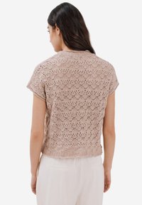 Kortärmad, stickad topp i ljusbeige med ett strukturerat, diamantformigt spetsmönster och en något beskuren passform vid midjan.