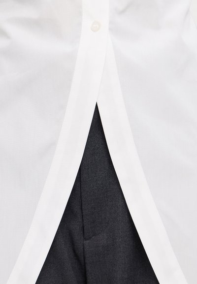 Weißes Hemd mit glatter Textur, unter dem ein kontrastierendes dunkles Gewebe sichtbar ist. Das Hemd hat einen geraden Saum und präzise Nähte.