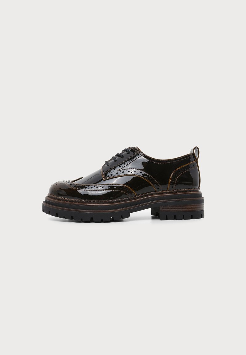 Μαύρο γυαλιστερό δερμάτινο παπούτσι brogue με παχιά σόλα με αυλακώσεις, λεπτομερείς ραφές, τρύπες και κλείσιμο με κορδόνια, εμφανίζεται από το πλάι σε λευκό φόντο.