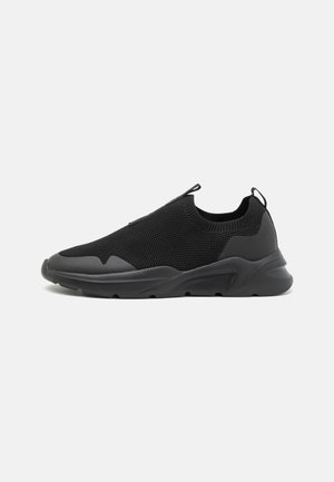 Czarne buty sportowe wsuwane, z teksturowanym materiałem siateczkowym, gumowymi detalami i grubą podeszwą o eleganckim, minimalistycznym wzornictwie.
