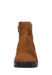 Bottine en daim marron, avec un bout rond, une fermeture éclair sur le côté et une semelle en caoutchouc noir texturé. Fini lisse et détails minimalistes.