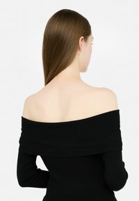 Top nero a spalle scoperte, maniche lunghe, design aderente, texture liscia, con un ampio scollo che mette in mostra le spalle e la schiena.