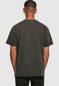 Sort, kortærmet T-shirt lavet af bomuld med en let falmet struktur. Har en rund hals og kontraststikninger langs sømmene.