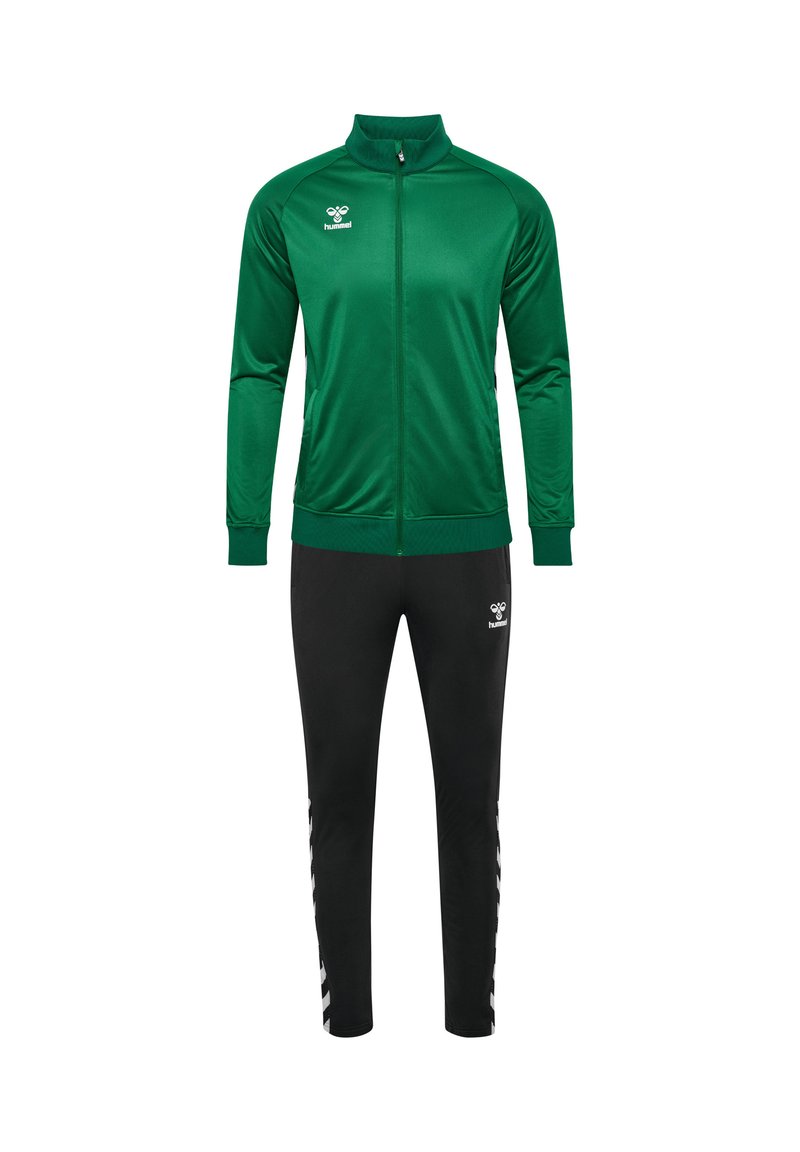 Groene ritsjack met hoge kraag, gecombineerd met zwarte tapered broek. Beide hebben logo-accenten. Soepele textuur, sportieve pasvorm.