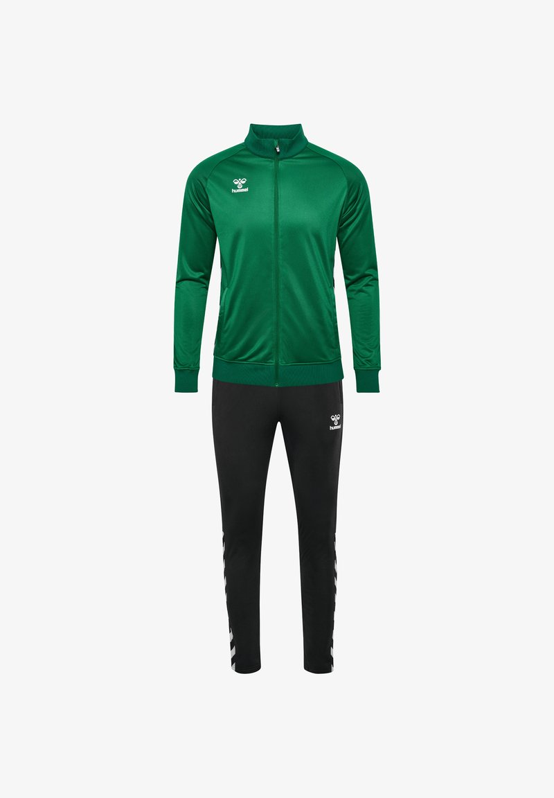 Groene ritsjack met hoge kraag, gecombineerd met zwarte tapered broek. Beide hebben logo-accenten. Soepele textuur, sportieve pasvorm.