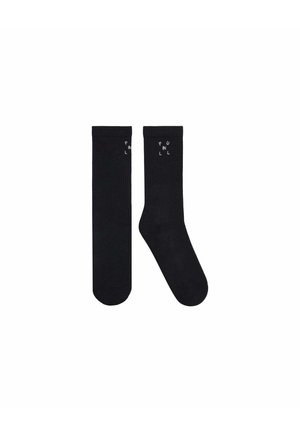 Deux chaussettes noires d’équipage, une plate et une inclinée, chacune avec un petit texte blanc « PULL IN » près du haut du bord-côte.