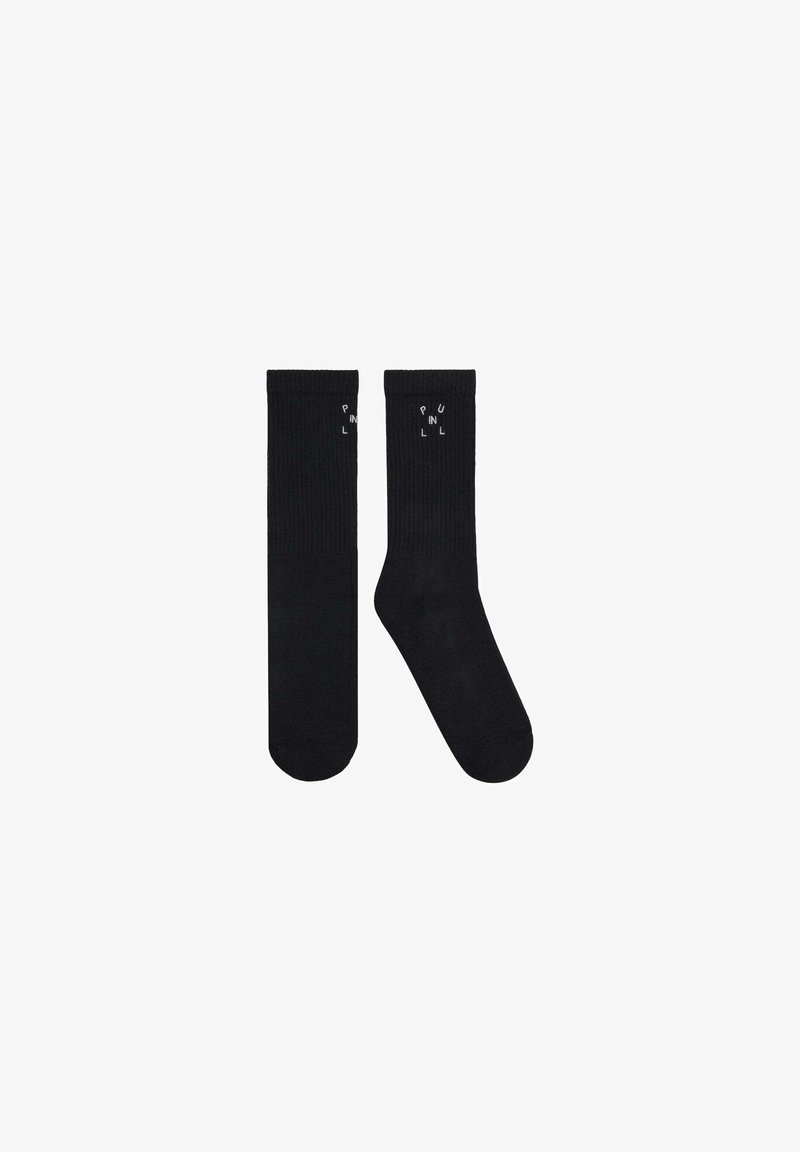 Deux chaussettes noires d’équipage, une plate et une inclinée, chacune avec un petit texte blanc « PULL IN » près du haut du bord-côte.