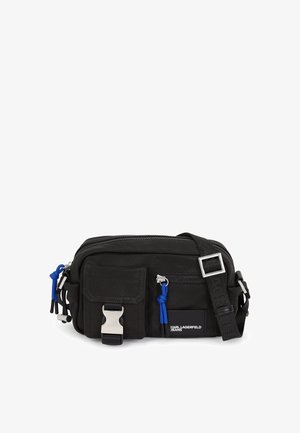 Melna auduma plecu soma ar rāvējslēdzēju, regulējamu siksnu, priekšējo kabatu un zilu akcentu. Iespējas ietver sudraba sprādzi un zīmola logo.