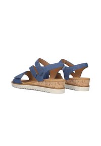 Blauwe denim sandalen met kurken sleehak, verstelbare banden, open teenontwerp en witte rubberen zool met een gestructureerd patroon.