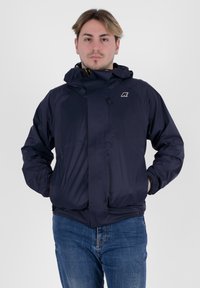 Giacca impermeabile blu navy con cappuccio, chiusura con zip, polsini elasticizzati e un piccolo logo sul petto. Texture liscia, design leggero.