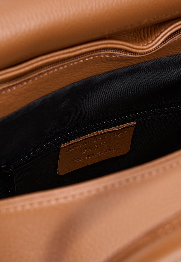 Innenraum der tanfarbigen Ledertasche mit schwarzem Futter. Verfügt über eine Reißverschlusstasche und ein Lederetikett mit der Prägung "maison héritage Paris."