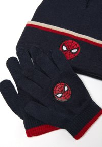 Gorro de punto azul marino con banda a rayas en color crema y rojo, que incluye un parche de Spiderman. Guantes a juego en azul marino con parche de Spiderman y detalles en rojo.