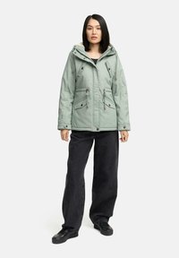 Mint green padded jacket with a hood, featuring two front pockets, drawstring waist, and metal hardware accents. Worn with black wide-leg pants.
