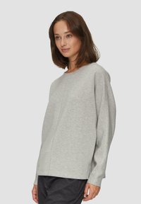 Lichtgrijze lange mouwen sweatshirt met een ronde halslijn en verlaagde schouders. Heeft een rechte snit en een zachte, gestructureerde stof.