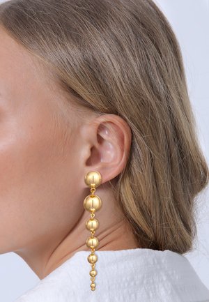Goldene Tropfohrringe mit einer Reihe von sphärischen Perlen, die in der Größe variieren, mit einer glatten, glänzenden Textur und einem verlängerten Design.