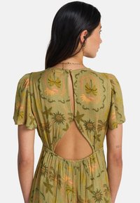 Πράσινο φόρεμα με υφασμάτινη υφή, κοντά μανίκια με φουσκωτό ύφος, άνοιγμα στην πλάτη και βοτανικά σχέδια σε πορτοκαλί και κίτρινο τόνους.