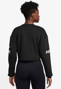 Zwarte cropped sweatshirt met een relaxte pasvorm, gemaakt van zachte stof. Beschikt over brede mouwen en een wit Nike-logo op de linkermouw.