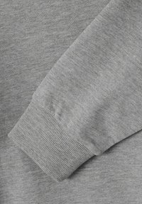 Manga de sudadera gris con puño acanalado y tejido suave y texturizado. Diseño simple con un color apagado, adecuado para uso casual.