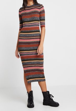Woman wearing a ribbed, striped midi dress with elbow-length sleeves paired with black lace-up combat boots.