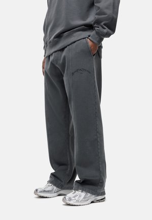 Grijze wijde broek van katoen met zijzakken, voorzien van zwarte geborduurde tekst "GOOD FOR NOTHING" op de linkerdij.