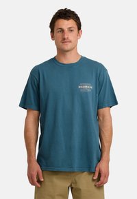 Turelkowy bawełniany t-shirt z okrągłym dekoltem, krótkimi rękawami i nadrukowanym logo na lewej klatce piersiowej. Luźny krój z gładką fakturą.