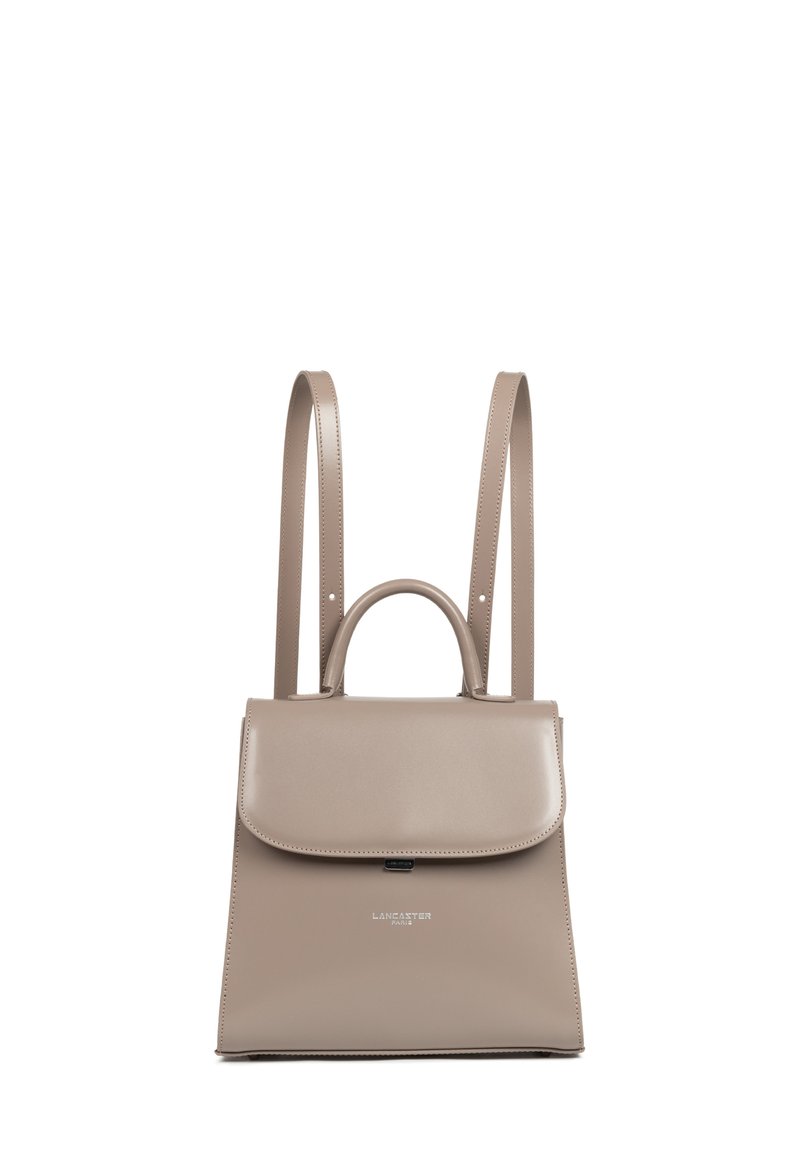Sac à dos en cuir beige au design structuré, avec un rabat supérieur plat, une poignée supérieure et des bretelles ajustables. Présente un logo à l'avant.