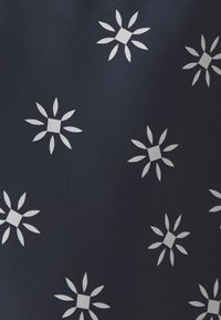 Marint tyg med ett upprepat vitt blommönster som har fyrkantiga mitten och avlånga bladliknande kronblad. Slät textur och jämn färg.