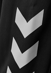 Black fabric featuring large white chevron patterns, with a textured surface visible in the weave of the material. Accents are bold and geometric.