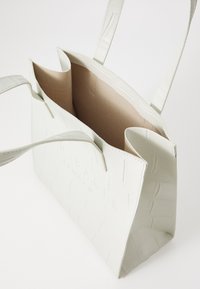 Strukturierte weiße Tote-Tasche mit einem strukturierten Krokodil-Muster, ausgestattet mit einem beigen Innenraum und doppelten Schultergurten. Offenes Design für einfachen Zugriff.
