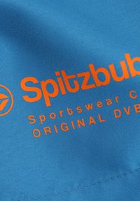 Blauwe stof met een oranje gedrukt logo dat "Spitzbub" leest, met daaronder "Sportswear Co." en "ORIGINAL DVE". Glad textuur, casual ontwerp.