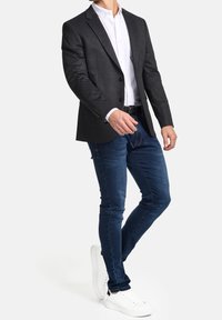 Šedý sako, bílé košilové triko, modré džíny, bílé tenisky. Sako má úzký střih, jednoradové zapínání a klopové límce.