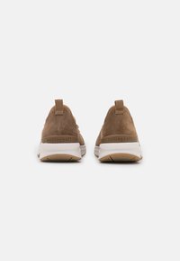 Braune Wildledersneaker mit strukturierter Oberfläche, niedrigem Profil, weißer Gummisohle und einer verstärkten Fersenlasche mit der Aufschrift "rollingsoft".