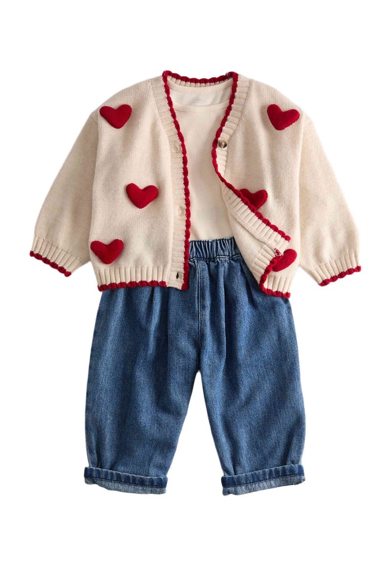 Cream cardigan with red heart patches and trim, paired with white long-sleeve shirt and blue rolled-hem denim pants for a child.