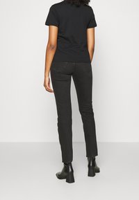 Black fitted t-shirt and black slim jeans, with subtle stitching and two back pockets, paired with black block-heeled ankle boots.
