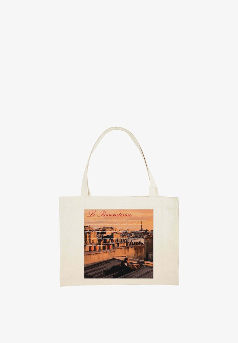 Sac fourre-tout en coton de forme rectangulaire, couleur crème, avec une image imprimée d'une skyline parisienne et le texte "Le Romantisme" en rouge.