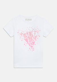 Balta īsroku T-krekls ar lielu rozā spīdīgu trijstūra dizainu, kurā redzams vārds "GUESS" un izkaisīti mazi rozā sirsniņas.