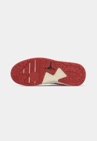 Suola della scarpa con una base in gomma rossa e motivi in rilievo, intersuola color crema e un accento con il logo Jumpman nero sul lato esterno.