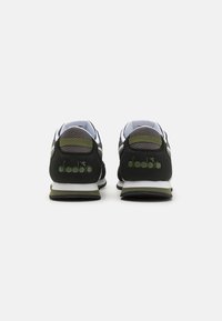 Scarpe da atletica nere e verdi con materiali in rete e suede, forma arrotondata, suola intermedia bianca e logo sul tallone.